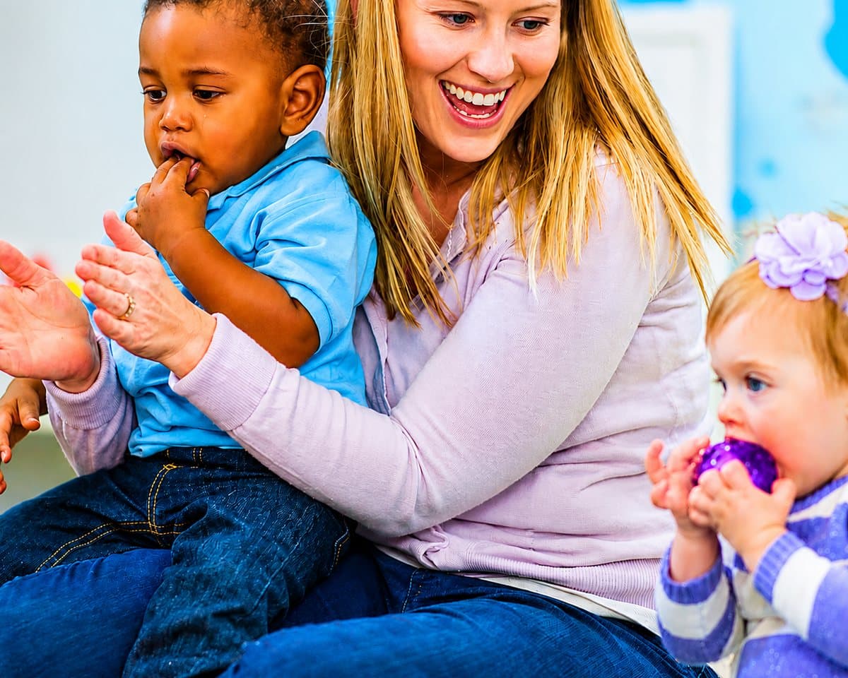 Pedagogisch medewerker met twee peuters op schoot